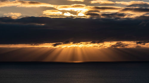 Scenic view of sea against dramatic sky during sunset