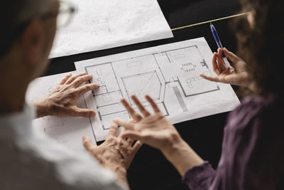 Business colleagues discussing over floor plan on table at office