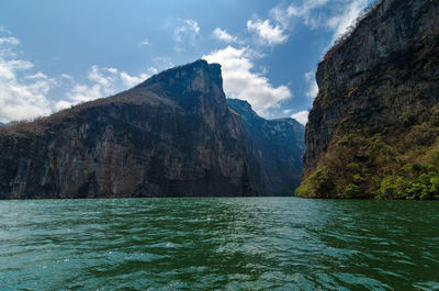 Scenic view of cliffs by sea against sky