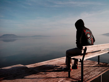 Man sitting on bench against sea