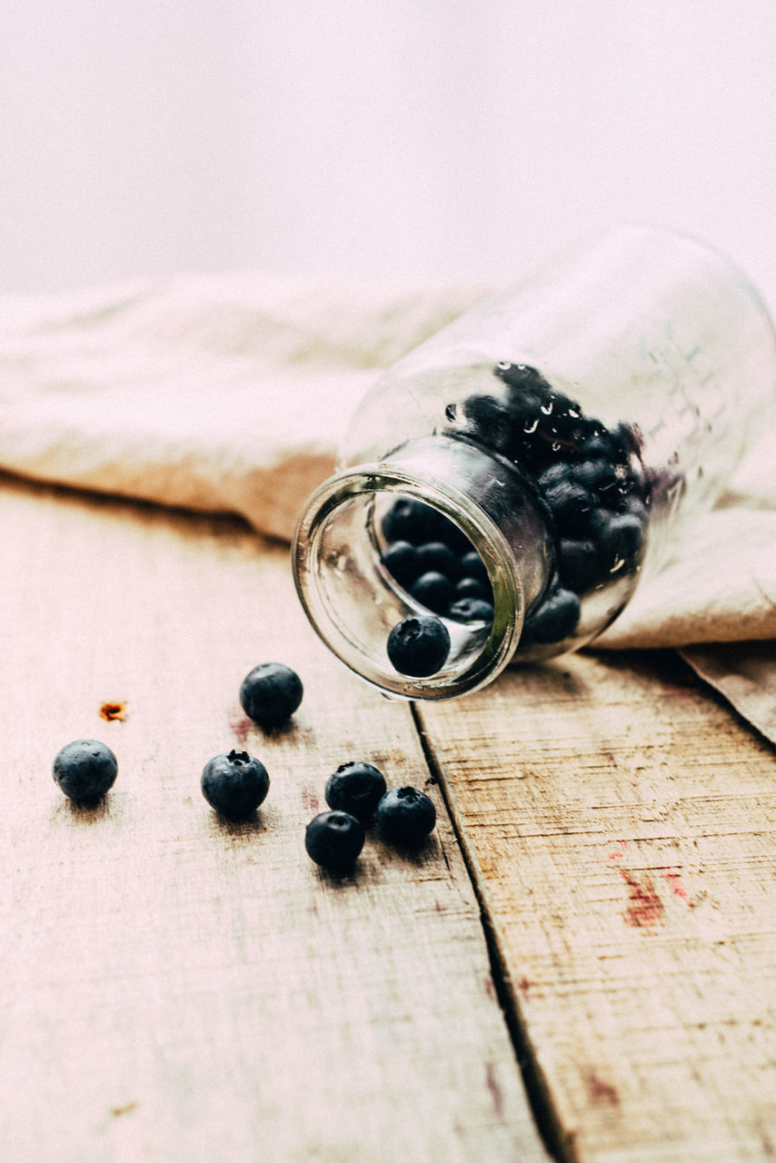 Blackcurrants rolling out of glass jar