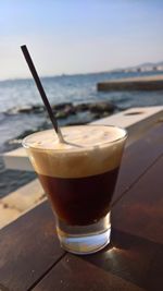 Close-up of drink on table at beach against sky