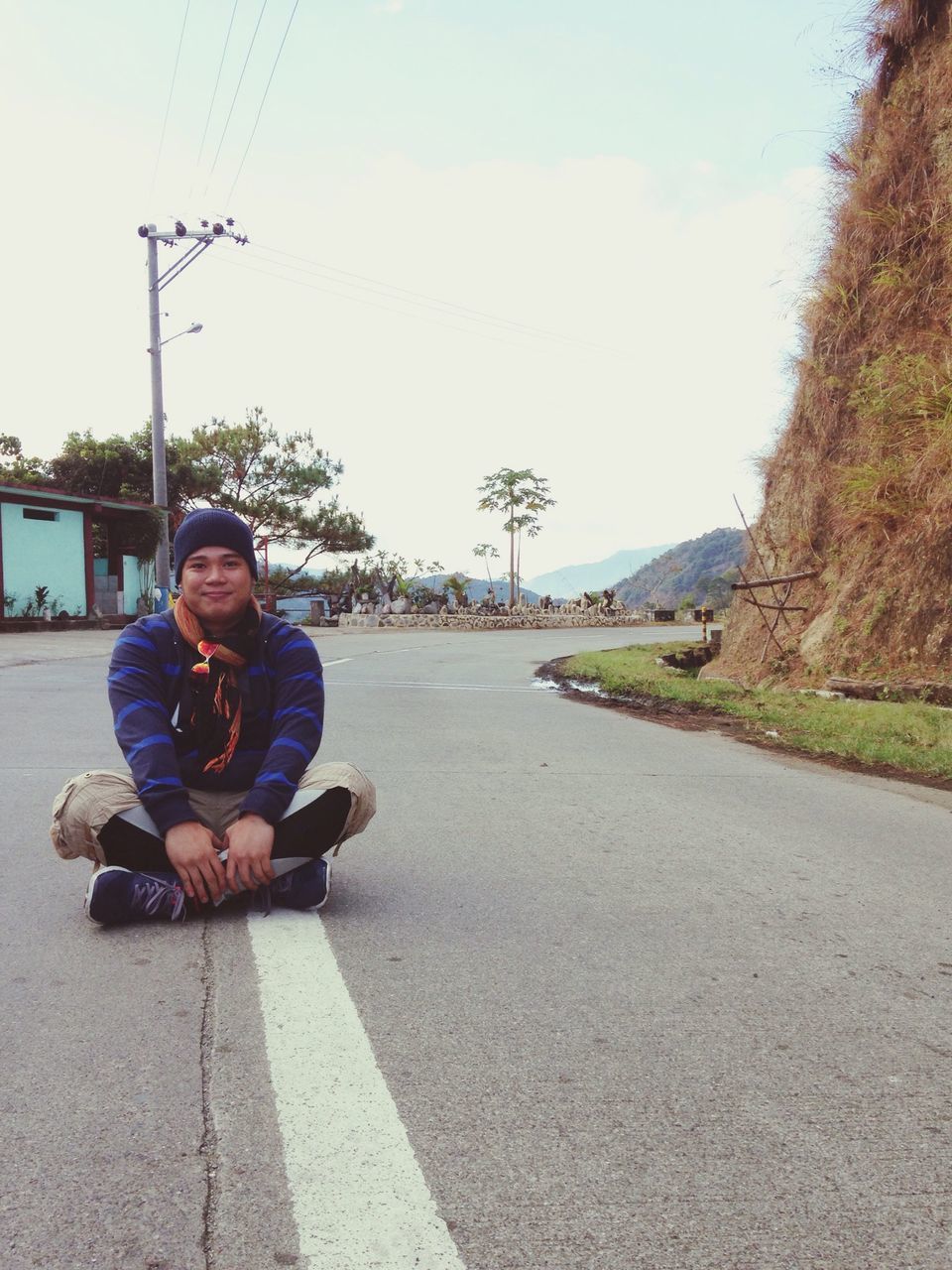 lifestyles, leisure activity, casual clothing, full length, person, sky, sitting, street, transportation, road, young adult, tree, clear sky, the way forward, day, outdoors, rear view, sunlight