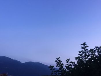 Low angle view of silhouette mountains against clear blue sky