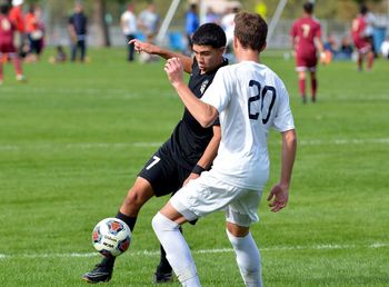 Full length of men playing soccer on field