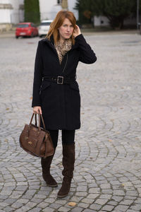 Portrait of young woman standing on cobble street