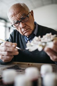 Senior man decorating ceramic in his spare time