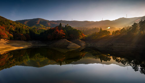 Scenic view of lake by mountains against sky during sunset