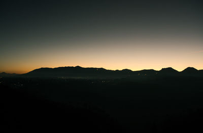 Scenic view of silhouette mountains against clear sky during sunset