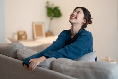 Cheerful woman sitting on sofa at home