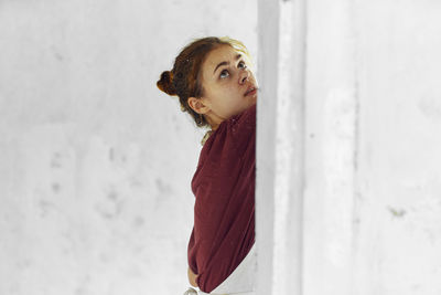 Young woman standing against wall