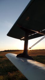 Close-up of airplane wing against sky during sunset