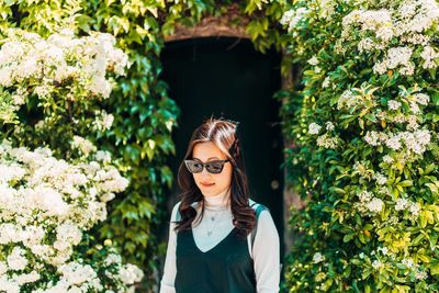 Woman in sunglasses by blooming flowers