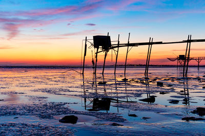 Abandoned pier over sea during sunset