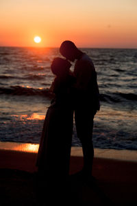 Couple standing on beach during sunset