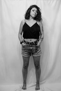 Portrait of young woman standing against wall