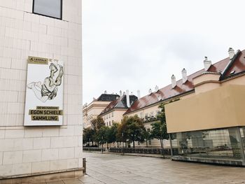 Text on wall in city against sky