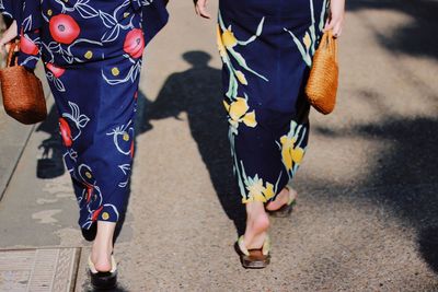 Low section of women walking on road