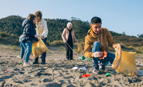 Grandparents and grandchildren cleaning at beach