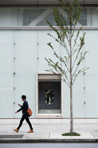 Full length of man walking on footpath against building