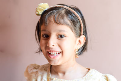 Close-up portrait of cheerful girl wearing headband at home