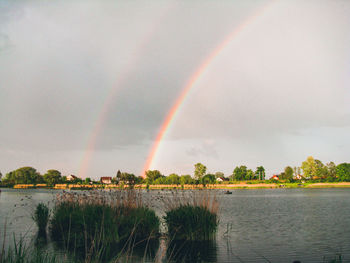 Scenic view of rainbow over lake against sky