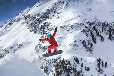 Full length person snowboarding on snowcapped mountain during winter