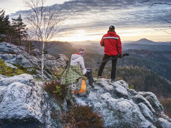 Rear view of men walking on rocks against mountains