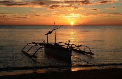 Silhouette fishing net on sea during sunset