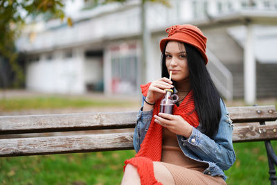 Portrait of young woman drinking juice while sitting outdoors