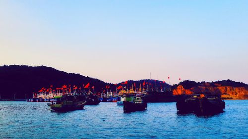 Boats sailing in river against sky during sunset