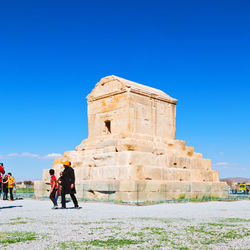 People walking in front of historical building against sky