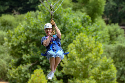Portrait of woman zip lining against trees