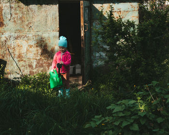 Girl came out of the barn with a watering can. harvest care. gardening with children