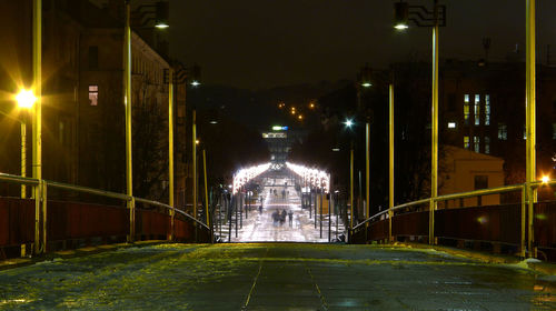 People on illuminated bridge at night