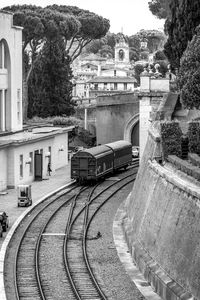 Train by railroad tracks in city against sky