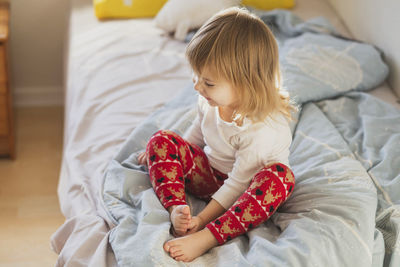 High angle view of boy playing with teddy bear on bed at home