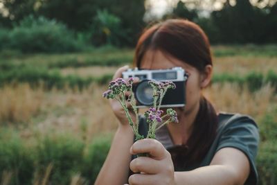 Woman photographing purple flowers on field