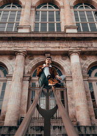 Low angle view of young man standing against building