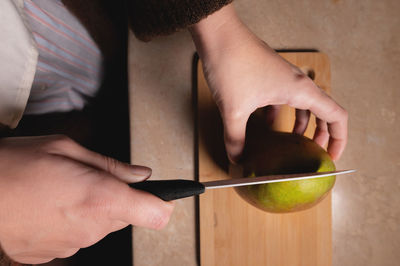 Top view woman cutting fruit on wooden board on table