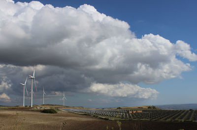 Wind turbines on land against sky