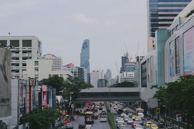 People on street amidst buildings in city against sky
