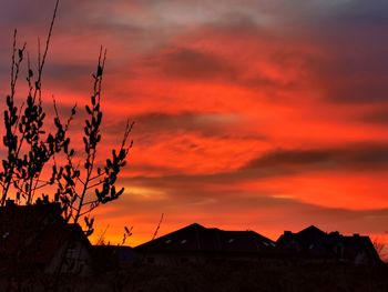 Silhouette houses against dramatic sky during sunset