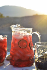 Pitcher and drink glasses of hibiscus flower iced tea in mojave desert setting