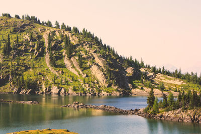 Scenic view of river by mountain against clear sky