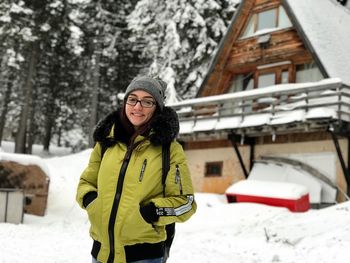 Portrait of smiling young woman standing in snow