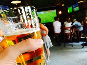 Midsection of man holding beer glass on table