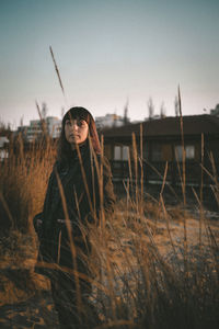 Woman standing on field against sky during sunset