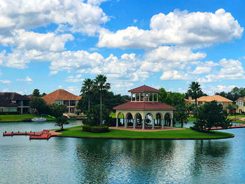 House by lake and buildings against sky