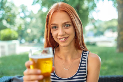 Portrait of smiling young woman holding beer in glass